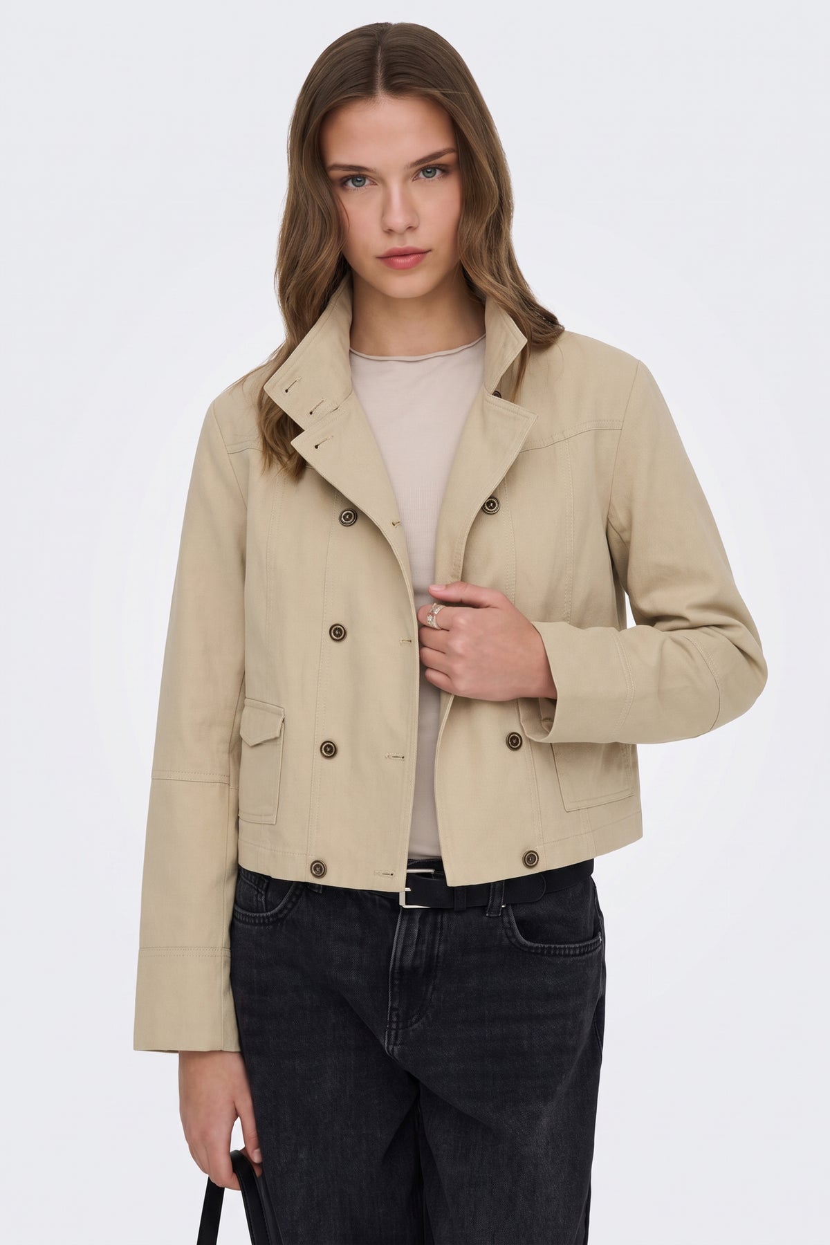 Beige cropped jacket worn open over a top