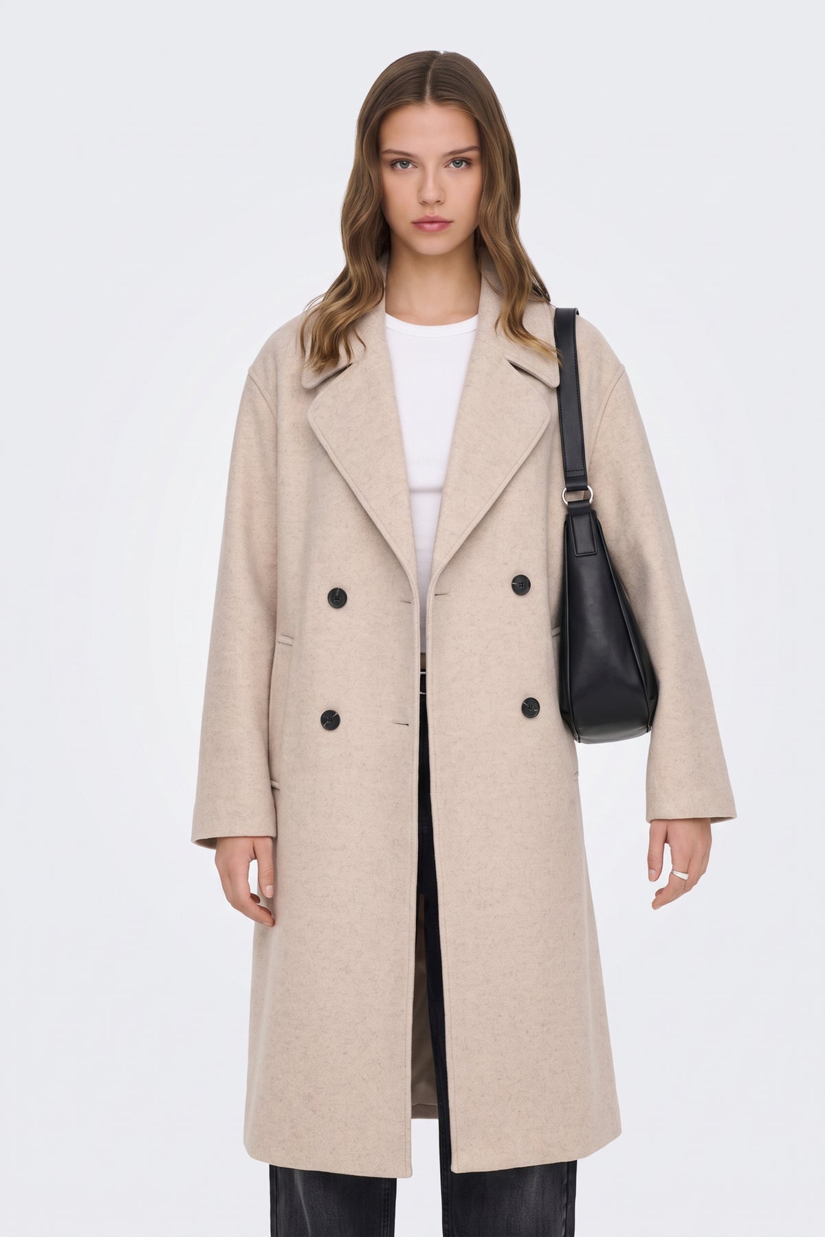Long beige double-breasted coat on model with black shoulder bag