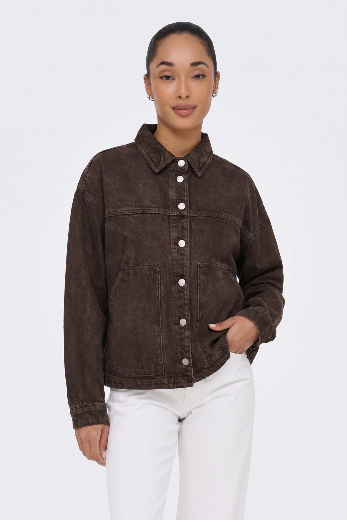 Brown washed denim jacket with white trousers, on model