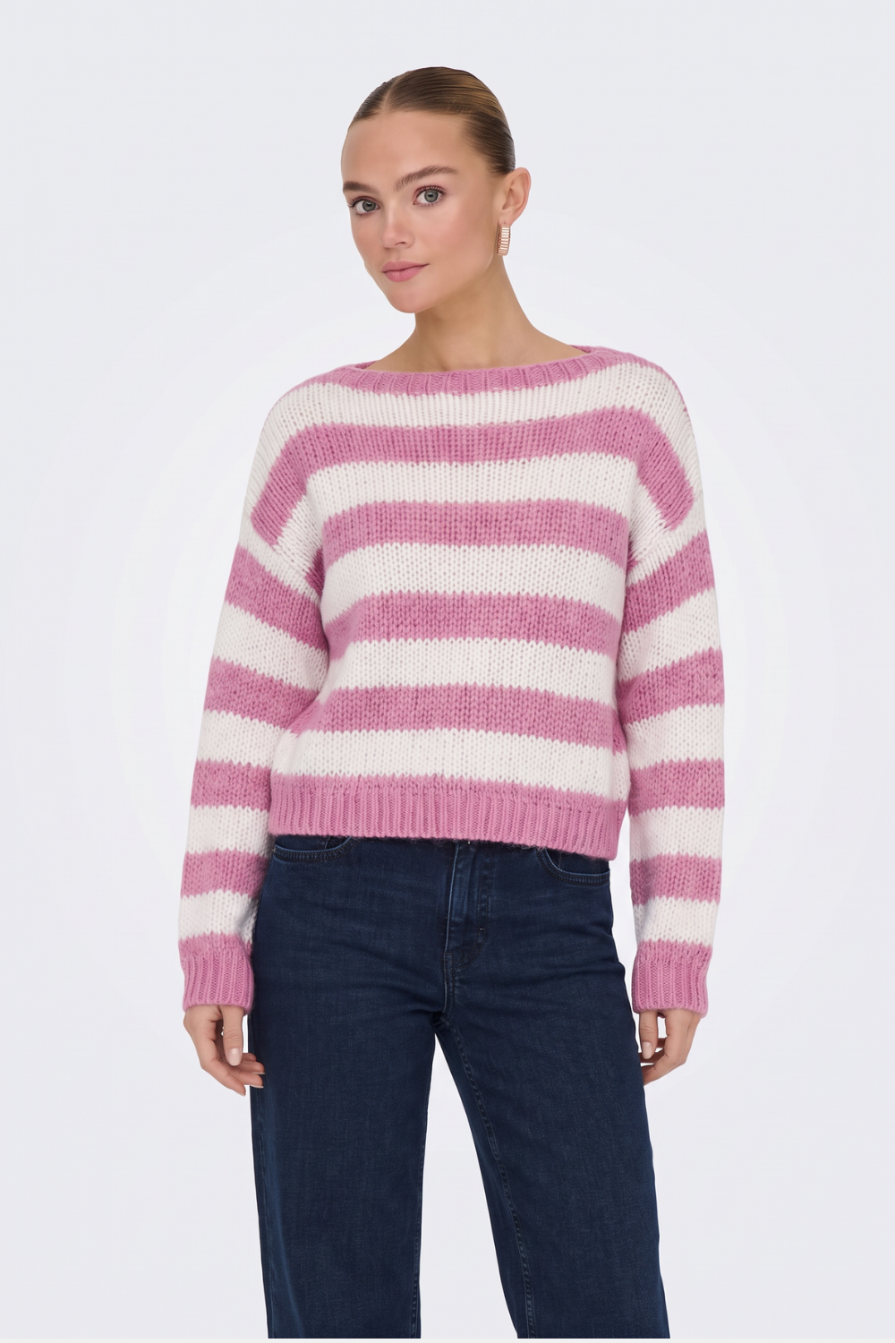 Pink and cream striped chunky knit jumper with dark jeans, on model