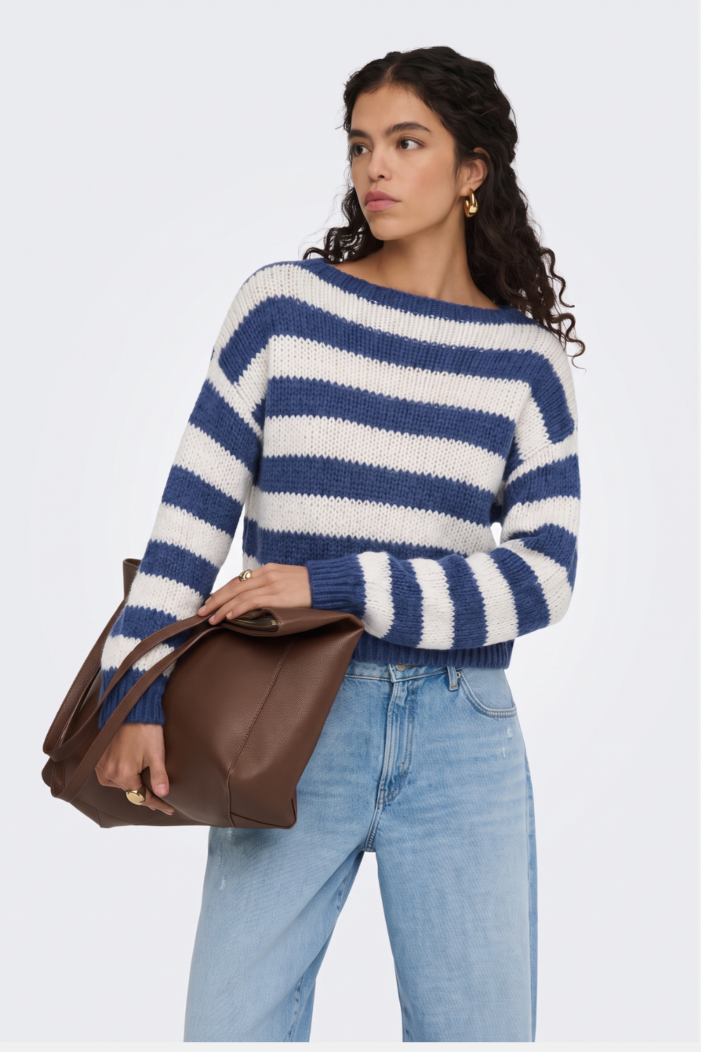 Blue and cream striped chunky knit jumper with jeans, on model