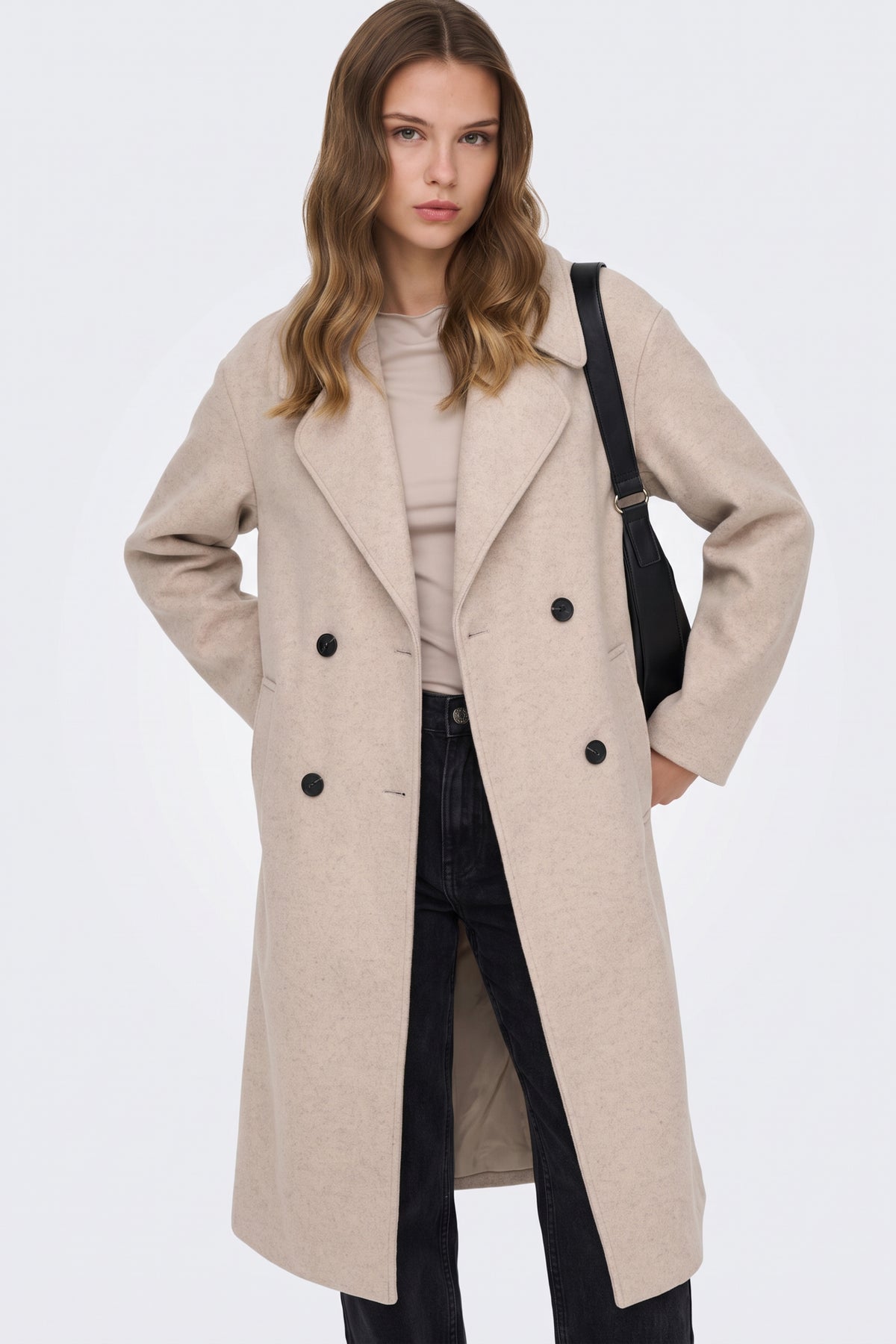 Long beige oversized coat worn open over jeans, on model