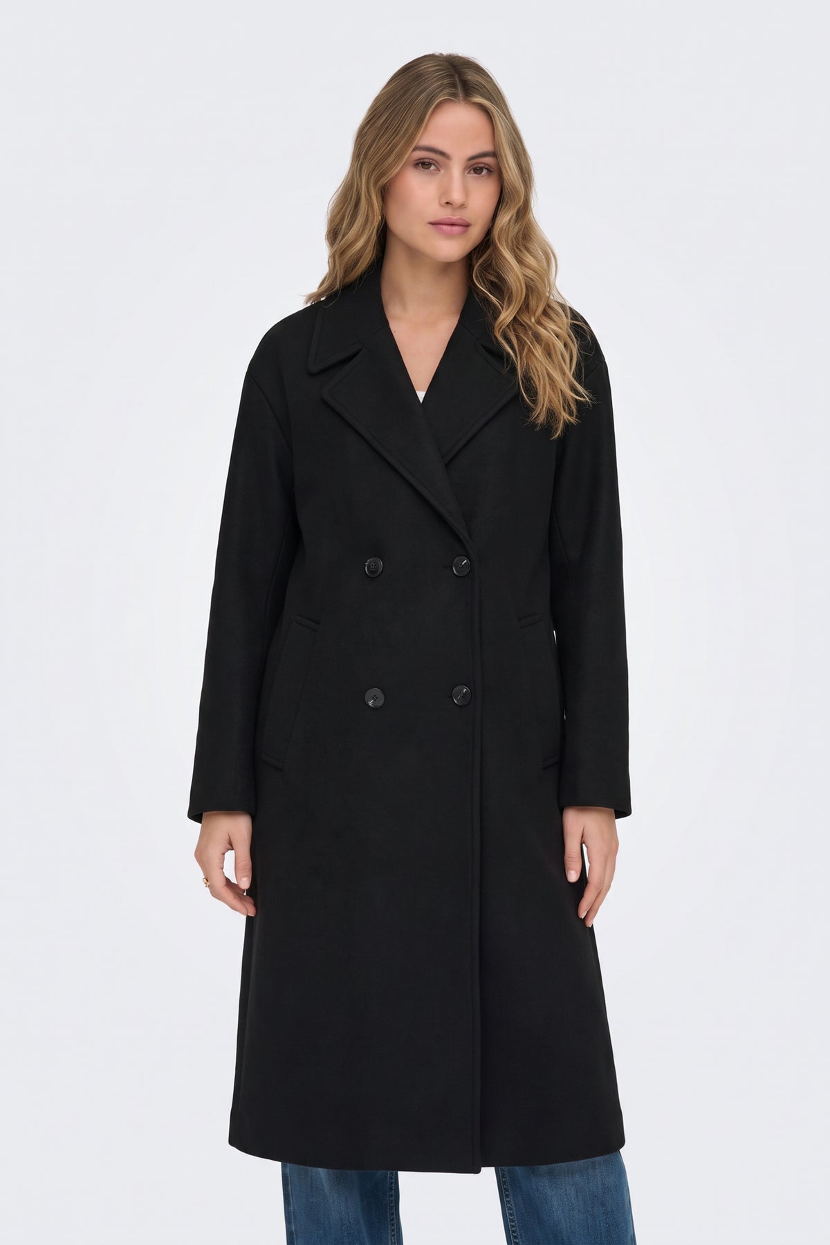 Long black double-breasted coat with blue jeans, on model