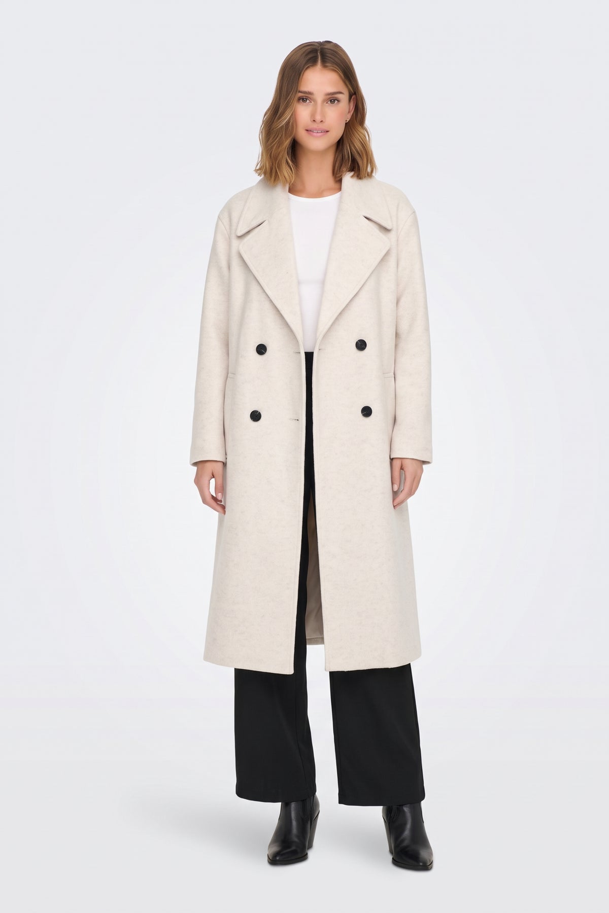 Long cream oversized coat worn open with black trousers, full length