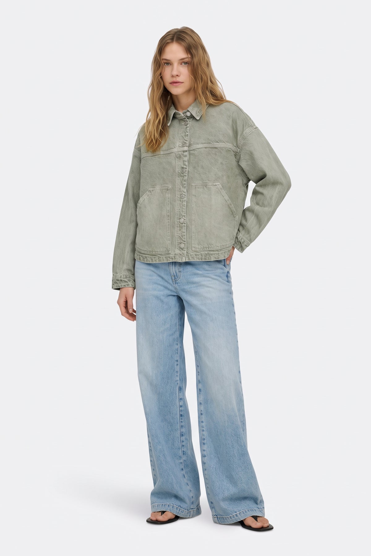 Sage green washed denim jacket with light wash jeans, full length on model