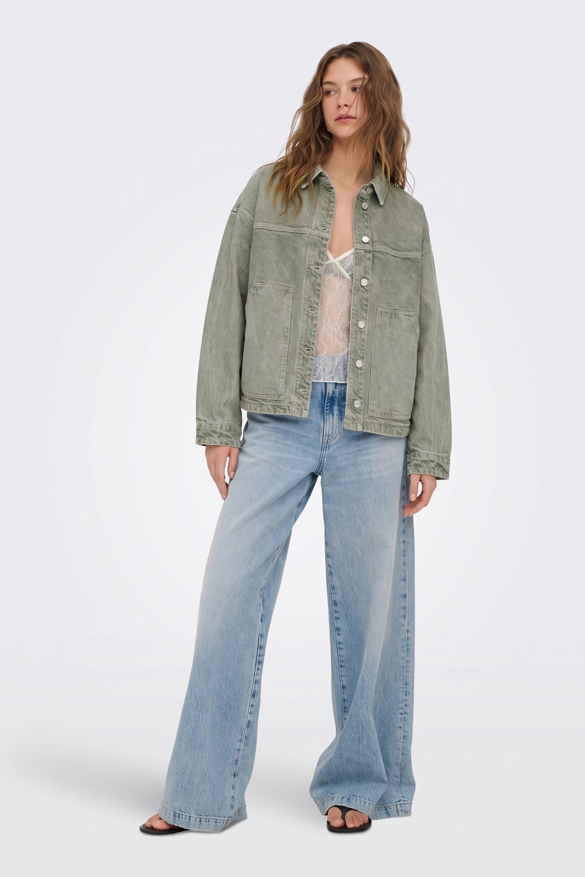 Green washed denim jacket worn open, full length on model