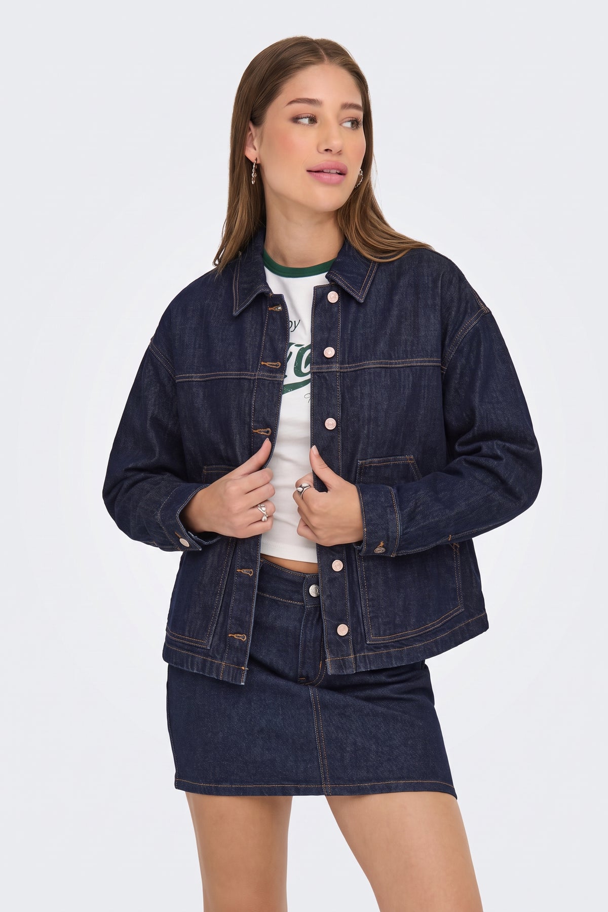 Dark blue denim jacket worn open over a white tee, on model