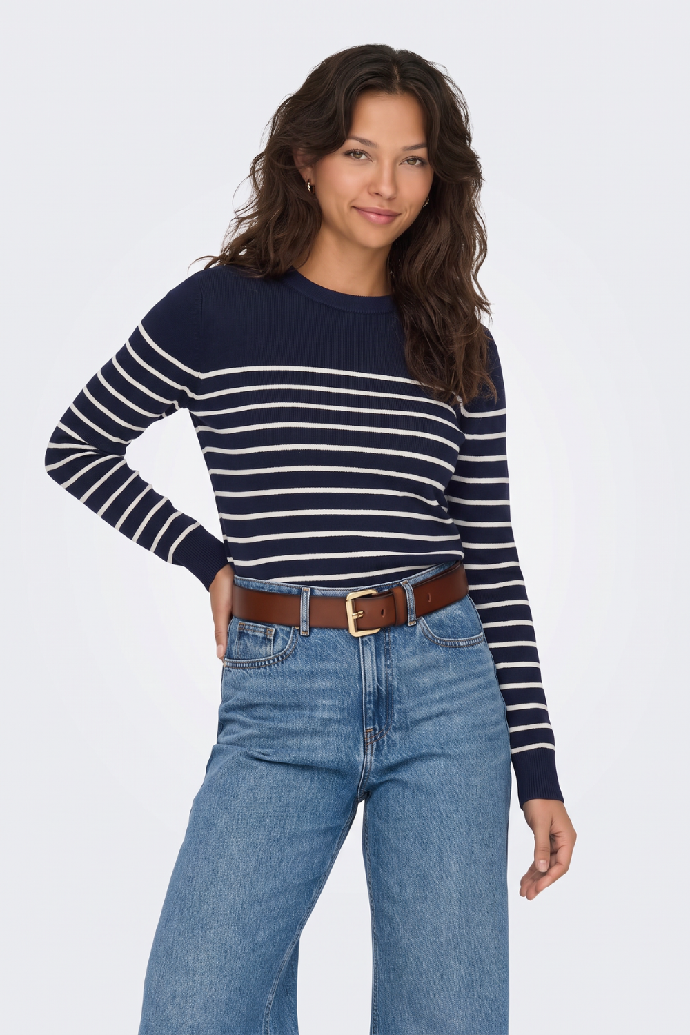 Navy and cream breton striped jumper with blue jeans and brown belt, on model